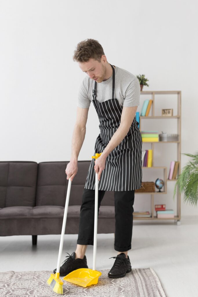 high angle man brooming floor